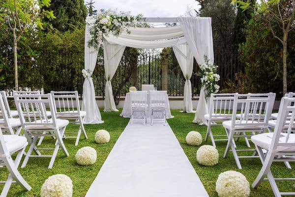 an intimate but luxurious outdoor wedding ceremony with white decor
