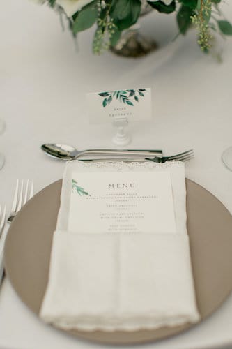 wedding place setting with custom menu and place cards set with a taupe charger plate and fancy napkin fold