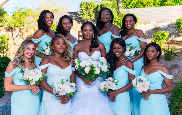 bridal party in teal dresses posing with bride before ceremony