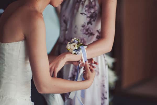 bride placing a wrist corsage on a special guest