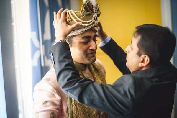 man helping South Asian groom dress for his Philadelphia wedding