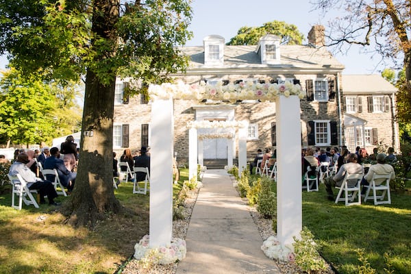 a line of elegant white wedding arches lining the aisle of a Philadelphia-home wedding