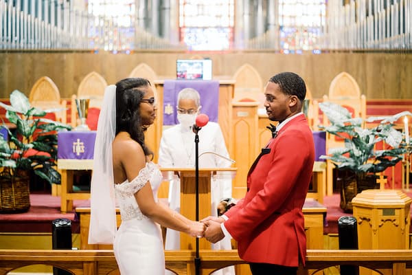 bride and groom exchanging wedding vows in a socially distant wedding ceremony officiated by a masked officiant at St Matthew AME in Philadelphia