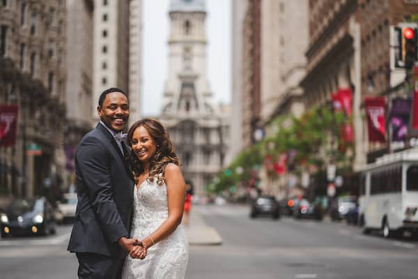 Brid mand groom in the middle of South Broad Street with Philadelphia City Hall in the background