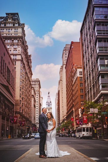 bride and groom on South Broad Stree with Philadelphia City Hall in the background