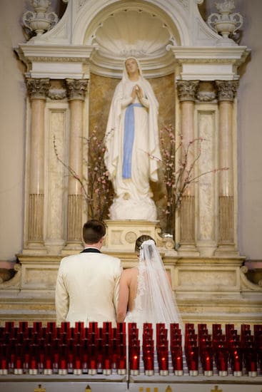 bride and groom in front of the Blessed Mother at The National Shrine of St Rita of Cascia