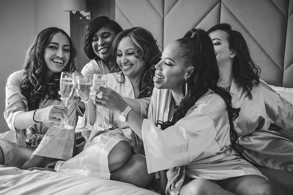 bride and her bridal party wearing robes and toasting with champagne