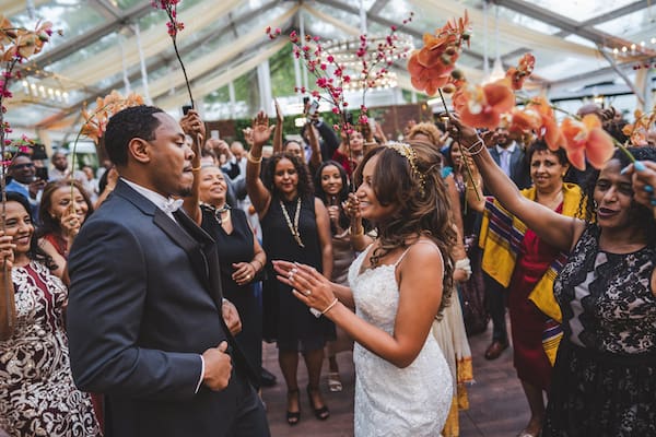 Philadelphia bride and groom entering under an arch of flowers to entered to an Eritrean song, ‘Lega Shibo’ by Hani Mihreteab