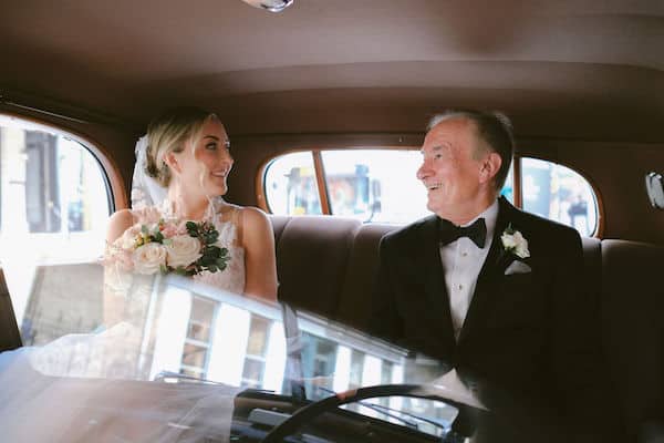 bride and her father in a vintage car on the way to her wedding ceremony