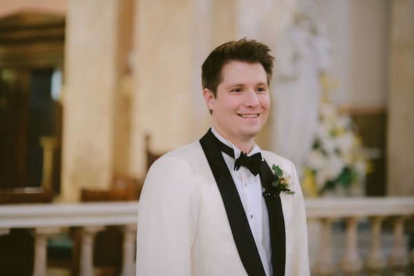 smiling groom as his wedding party enters the church