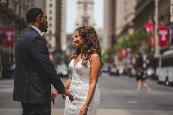 smiling bride and groom standing in the middle of South Broad Street during their first look