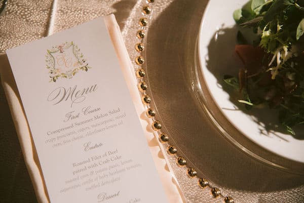 custom menu cards and a salad on a gold rimmed charger plate at a wedding at the Please Touch Museum