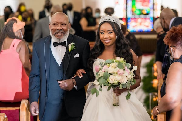 father walking his smiling daughter down the aisle 