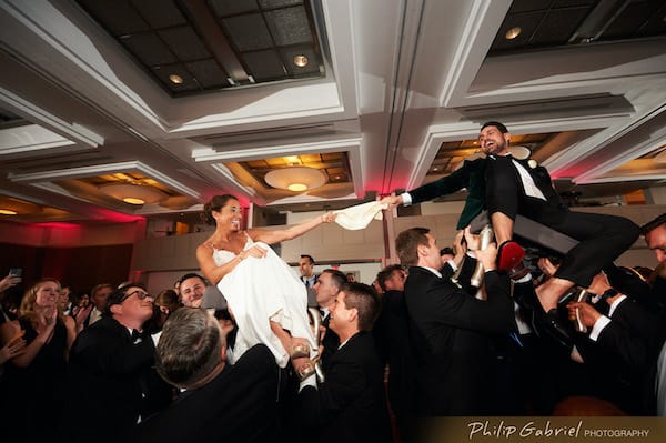 Bride and groom lifted in chairs during a hora at their Hilton Penn's Landing weding