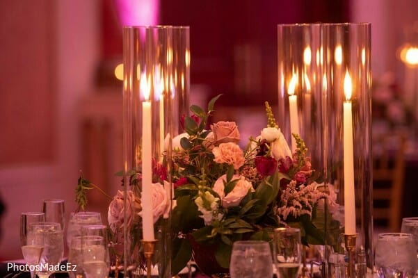 Floral centerpieces with taper candles in hurricane globes