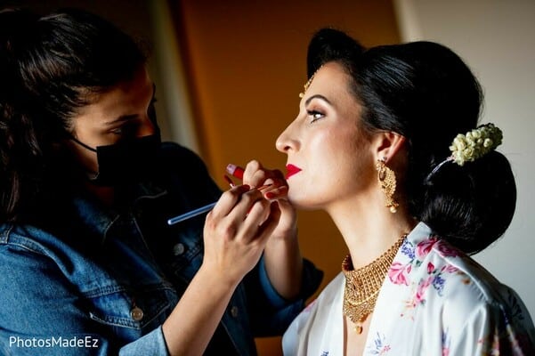 makeup artist applying lipstick to a beautiful bride