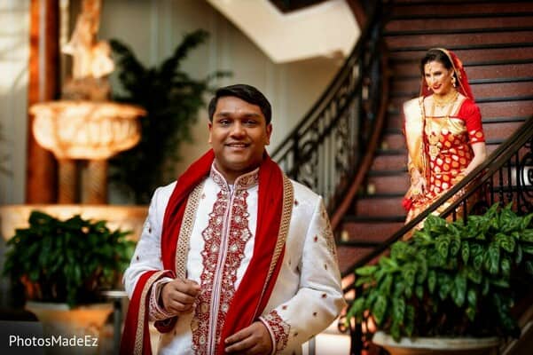 Indian groom waiting as his bride to be walks down the stairs behind him