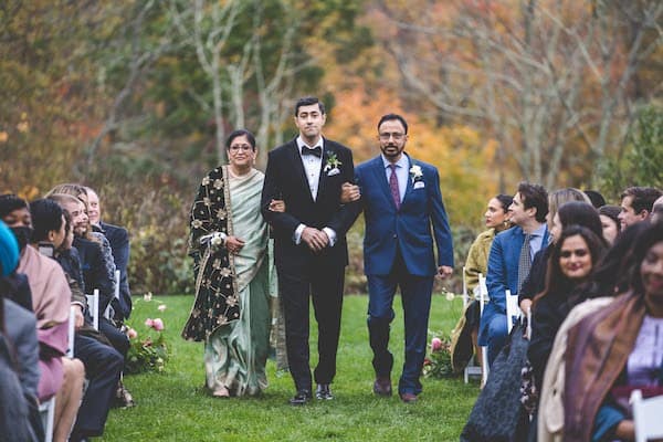 Indian groom being escorted down the aisle by his parents during his western wedding ceremony