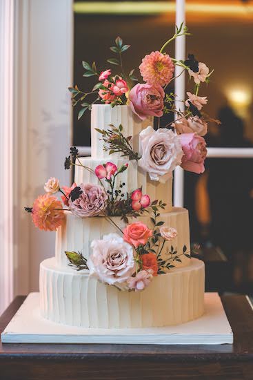 four tiered buttercream wedding cake decorated with fresh flowers