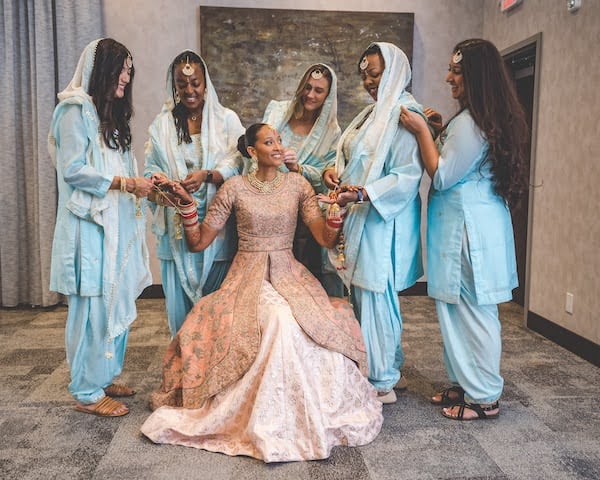 Bride in traditional Indian wedding attire surrounded by her bridal party