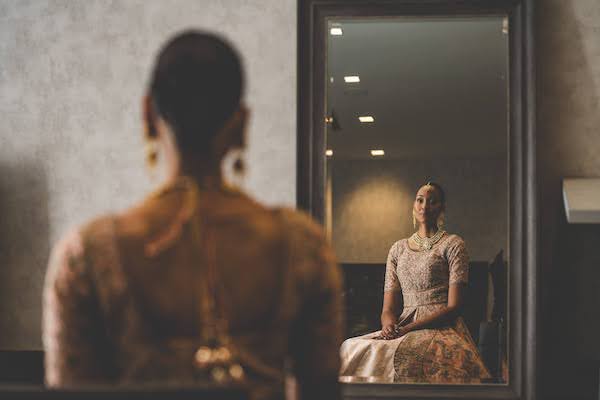 Bride in traditional Indian wedding attire looking in the mirror