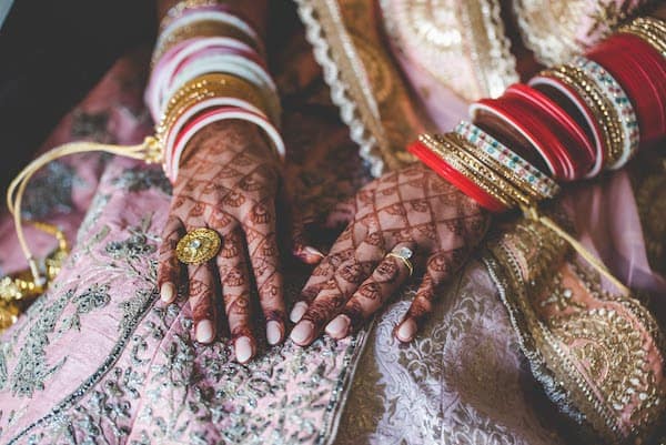 Indian bride's hands covered with henna and adorned with bangle bracelets