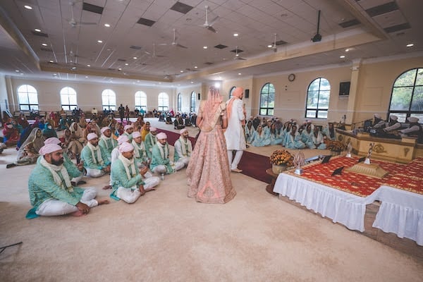 bride walking behind her groom in a Sikh wedding ceremony