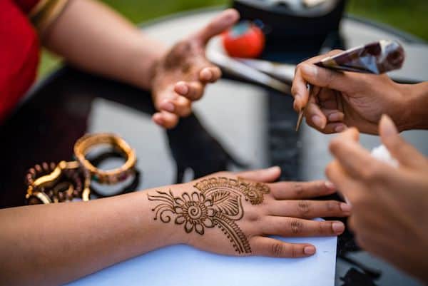 Henna artist applying henna at a South Asian multicultural wedding 